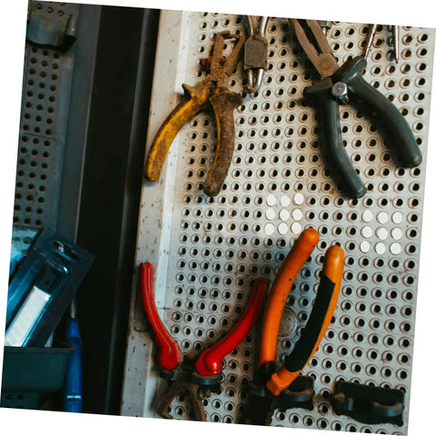 Assorted pliers hanging on perforated panel with tools nearby, ideal for use with 100 Pcs Plastic Hole Plugs White Screw Cap Covers.