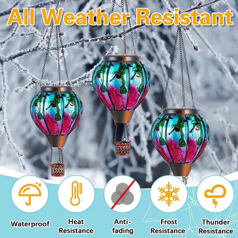 2 Pcs Glass Hot Air Balloon Solar Lanterns With Flickering Flame Hummingbird Design hanging outdoors in snowy weather