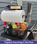 Grill Caddy For Outdoor Grill And BBQ Magnetic Tool Holder With Paper Towel Arm, filled with condiments and utensils on a grill.