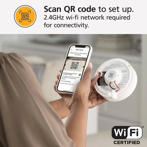 Person holding 2 In 1 Smoke Detector And Indoor Air Quality Monitor With WiFi And Alexa Compatibility showing QR code on phone for setup.