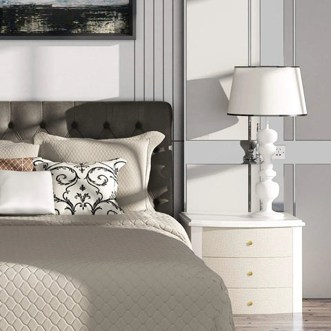 Bedroom with padded headboard, bedside table, white lamp, and decorative pillows, elegant contemporary design.