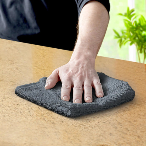 Hand wiping surface with gray towel from Pack Of 60 14 By 17 Inch Bar Towels For Cleaning 100 Percent Cotton Absorbent And Reusable Multipurpose Terry Cloth Shop Rags Gray Great For Heavy Duty Cleaning Spills And Damp Surfaces In Home Garage And Workshop
