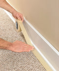Person applying masking tape for office and home projects with strong adhesive 0.70 inch by 54.6 yard along skirting board on carpet