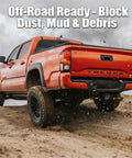 Orange truck with Limited Edition American Flag Trailer Hitch Cover Honoring 250 Years Of Freedom in off-road setting