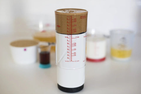 Two Cup Adjustable Measuring Cup with grippy rotating body filled with peanut butter, showing measurement markings.