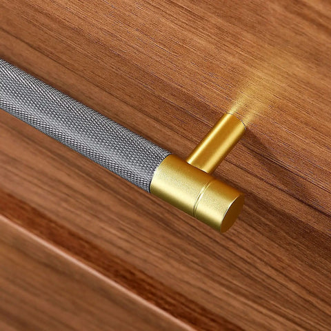 Close-up of grey and brushed nickel cabinet pull with knurling pattern on wooden surface