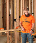 Man holding heavy duty wire dispenser for stud framing mounts to 2x4 and 2x6 wood studs with solid steel construction.