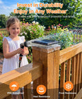 Child spraying water on a 12 Pack Solar Post Cap Lights For 4x4 Posts No Wiring Needed Waterproof Warm White LEDs 360 Degree Illumination Fits 3.5x3.5 And 4x4 Wood Or Vinyl Fence Deck Posts Ideal For Patio Porch Outdoor Lighting installed on a wooden deck post.