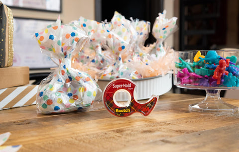 Super Hold Tape With 50 Percent More Adhesive, Clear Finish, 2 Rolls, Dispenser Ready on wooden table with gift bags