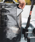 Person placing phone in ExoDry 30L Large Drybag With Roll Top Closure Waterproof 500D PVC on boat, showcasing waterproof feature.