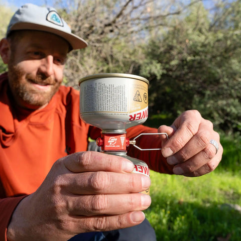 Person using the Fuel Transfer Kit For Backpacking And Camping With Flow Control Valve And Integrated Pressure Vent outdoors.