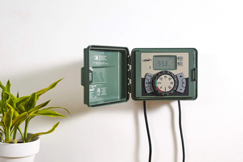 Four Station Outdoor Sprinkler Timer With Swing Panel For Lawn Care, mounted on a wall, open green weatherproof cabinet
