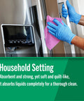 Front view of gloved hands wiping a stainless steel refrigerator with pink Fresh Towel reusable paper towels.