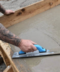 Worker using Pro-Grade Magnesium Concrete Float 3-1/8 x 16 In with beveled ends on fresh concrete slab surface