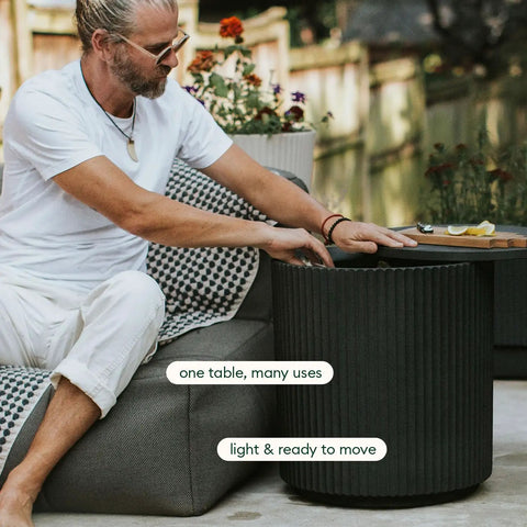 Person using 2-In-1 Outdoor Cooler Side Table in Black, keeps 48 cans cold, 40L ice capacity, ideal for relaxation on patio or deck.