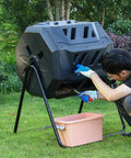 Man using an Outdoor 160L Rotating Compost Tumbler Bin For Garden And Yard Waste on grass with pink collection bin