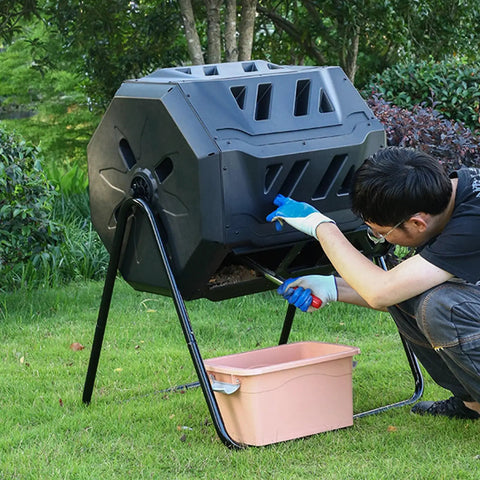 Man using an Outdoor 160L Rotating Compost Tumbler Bin For Garden And Yard Waste on grass with pink collection bin