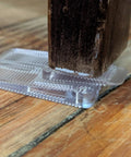 Kick Those Wobbles To The Curb With This Solid Thirty Four Piece Plastic Shim Kit using a clear shim under a wooden furniture leg.