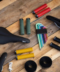 Assorted bike accessories including seats, grips, and tools on a wooden surface, excluding Pocket-Ready Aluminum Chain Splitter.
