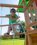Child climbing rope ladder on Cedar Wood Swing Set With Wave Slide And Elevated Play Deck, Double Rock Wall, Rope Ladder, Web Swing And Belt Swings, Toy Telescope, Steering Wheel, Sandbox Area For Backyard Adventure And Kid Approved Outdoor Fun