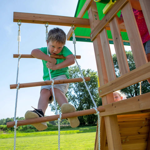 Child climbing rope ladder on Cedar Wood Swing Set With Wave Slide And Elevated Play Deck, Double Rock Wall, Rope Ladder, Web Swing And Belt Swings, Toy Telescope, Steering Wheel, Sandbox Area For Backyard Adventure And Kid Approved Outdoor Fun