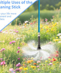 RV black tank cleaning wand with blue braided hose spraying water in a field of flowers