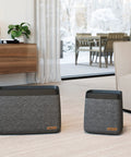Living room with two modern black and gray air purifiers on carpet near glass doors and wooden furniture.