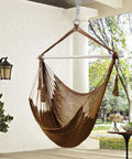 Caribbean Style Rope Hammock Chair With 40 Inch Steel Spreader Bar And Anti Slip Rings Soft Spun Cotton Rope For Indoor Outdoor Backyard Chill Relaxation Supports Up To 500 Lbs Tan hanging in a patio
