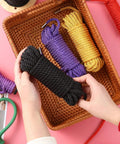 Soft Silk Bondage Rope Set 32 Feet Each 8mm Thick Two Pack For BDSM Shibari Play held by hands in basket with colorful ropes