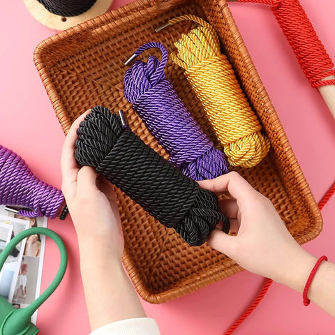 Soft Silk Bondage Rope Set 32 Feet Each 8mm Thick Two Pack For BDSM Shibari Play held by hands in basket with colorful ropes