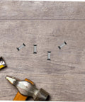 Knife handle rivets, four pieces, stainless steel; top-down close-up with hammer and measuring tape on wood surface.