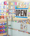 An office supplies store interior with an 'OPEN' sign above the entrance, showcasing shelves of colorful stationery.