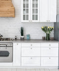 Slick Brushed Nickel Round Zinc Cabinet Knobs Delivering Fresh Euro Style Vibes For Modern Kitchen Or Bathroom Setups Sweet Smooth Finish In Top Shelf Twenty Piece Pack Ready For Fast Upgrades adorning a white kitchen.