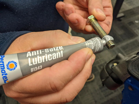 Permatex Anti-Seize Lubricant 1 oz tube; gray label with blue logo, applied to a threaded bolt.
