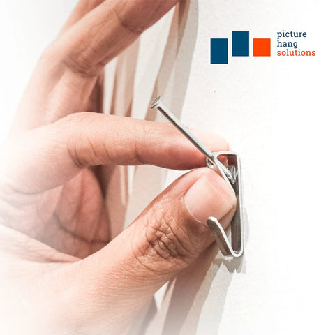 Hand installing Heavy Duty Picture Hooks For Walls With 50 Lb Capacity Durable Drywall Hangers And Nails Includes 1000 Hooks And 100 Nails