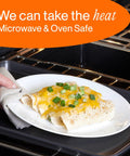 Person removing a plate with cheesy enchiladas from the oven, demonstrating microwave and oven safe dinnerware.
