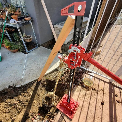 Beefy 48 Inch Ratcheting Off Road Utility Farm Jack in action, red finish, lifting setup in outdoor environment, side view