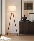 Tall Tripod Floor Lamp With Wood Legs And Cream Drum Shade, Modern Mid Century Style LED Lamp For Living Rooms, Bedrooms, And Home Offices, Walnut Brown Finish For A Cozy Reading Light Vibe, shown next to a sideboard in a bright room.