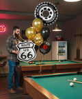 Man with Route 66 Retro Party Balloons Kit With Vintage Car Tire Decor And Vinyl Record Foil Balloons by a pool table