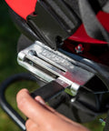 Close-up of hand operating Pro Grade Chest Mount Hand Crank Spreader With Even Spread Technology 40 lb hopper in backyard setting.
