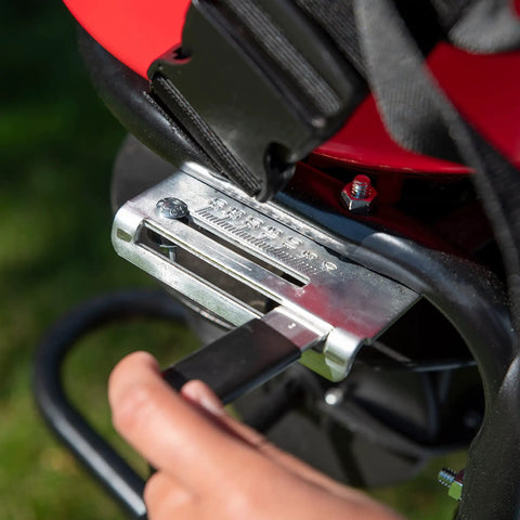 Close-up of hand operating Pro Grade Chest Mount Hand Crank Spreader With Even Spread Technology 40 lb hopper in backyard setting.