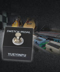 Tap Switch Pedal For Guitar Effects Latch Footswitch With 1/4 Inch TS Cable in a studio setup with guitars in the background
