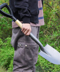 Person holding a round small shovel with wooden D handle for digging and planting, 28 inch carbon steel garden shovel with rust resistant blade.