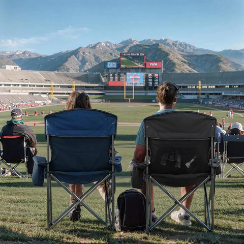 Two people seated on oversized folding camping chairs with 500 lbs support, black, at a sports event