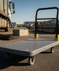 Heavy Duty Folding Flatbed Cart With Perforated Deck, 6-Inch Quiet Wheels And Brakes, Sturdy Hand Truck Trolley For Warehouse, Garage Or Home Use, Red Finish, Foldable Handle For Easy Storage And Smooth Rolling, shown on concrete yard