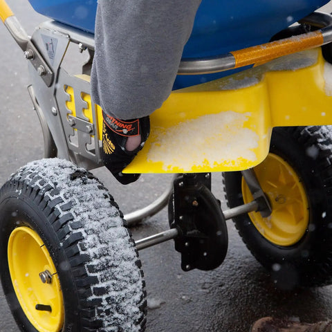 Close-up of Spyker Winter Weather Deicing Kit With Ergo Pro 50 Pound Spreader in snowy conditions, showing stainless steel agitator.