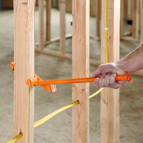 Hand using Heavy Duty Wire Dispenser For Stud Framing Mounts To 2x4 And 2x6 Wood Studs With Solid Steel Construction