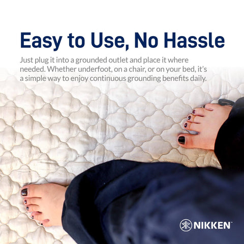 Feet resting on KenkoGround Grounding Mat for everyday recovery and calm vibes at home or office, 18 by 36 inch black grounding pad.