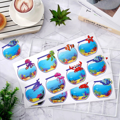 160 Ocean Animals Name Tag Stickers Set With Eight Cute Sea Creature Designs For Back To School on display with coffee and plants