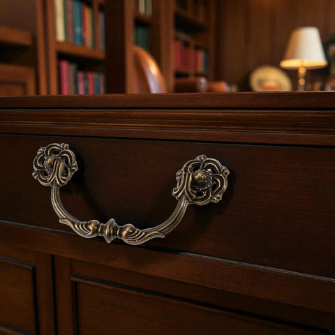 4-Pack Antique Brass Drawer Pulls 4.5 Inch Center-to-Center Drop Bail Dresser Handles Vintage Style Bronze Look Hardware for Cabinets Desks and Dressers 107mm Centers Zinc Alloy Construction Durable Ornate Finish installed on a wooden drawer in a classic study room.